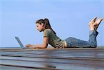 Woman Lying on Dock, Using Laptop