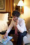 Businessman with Cellular Phone And Map in Hotel Room