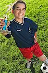 Garçon avec un ballon de Soccer et trophée