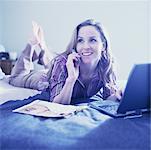 Woman on Bed with Cellular Phone And Laptop Computer