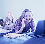 Woman on Bed with Cellular Phone And Laptop Computer