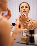 Femme regardant dans le miroir, application de maquillage