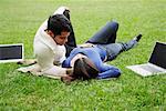 Couple Lying on Grass with Two Laptops