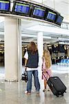 Garçon et fille regarder des données de vol dans l'aéroport