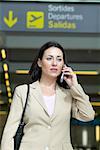 Frau mithilfe von Handys in Flughafen