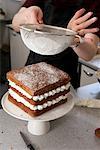 Frau sieben Puderzucker auf Kuchen