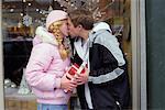 Young Couple Kissing While Holding Christmas Presents