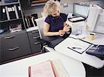 Businesswoman Filing Fingernails at Desk