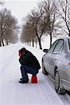 Mann mit dem steckengebliebenen Auto im Winter
