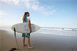Femme sur la plage avec planche de surf