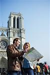 Couple Looking at Map by Notre Dame Cathedral, Paris, France