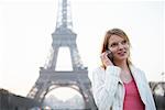 Femme utilisant un téléphone cellulaire de la tour Eiffel, Paris, France