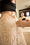 Couturière aidant femme Try sur la robe de mariée