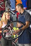 Man Showing Woman a Wheel in Bike Shop