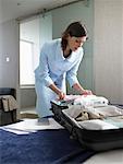 Businesswoman Packing Suitcase in Hotel Room