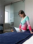 Woman with Laptop Computer in Bedroom