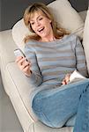 Woman on Sofa with Book and Cellular Phone