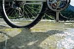 Close up of a person cycling across a stream