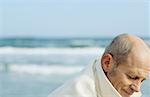 Senior man at beach looking down