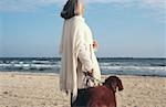 Senior woman walking dog at the beach