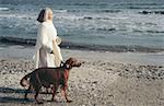 Senior woman walking dog by the sea