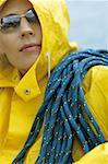 Woman in yellow raincoat and sunglasses with rope over her shoulder