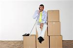 Businessman Using Telephone While Sitting on Boxes