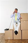 Businessman Using Telephone While Sitting on Boxes