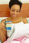 Woman Reading News Paper in Bed