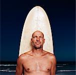 Homme avec planche de surf à la plage