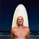 Homme avec planche de surf à la plage