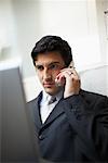 Businessman Using Cellular Telephone and Laptop Computer