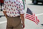 Back View of Man Holding American Flag at Fourth of July Parade