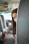 Girl Peeking from Behind Seat on School Bus