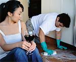 Woman Drinking Wine while Man Scrubs Floor