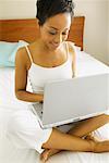 Portrait of Woman Sitting on Bed Using Laptop Computer