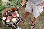 Woman Barbecuing Steaks and Vegetables