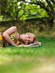 Porträt Frau liegend auf Gras mit Buch