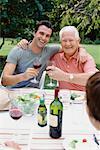 Père et fils adulte, boire du vin à dîner en plein air en famille