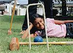 Girl Lying on Grass with Croquet Equipment