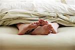 Close-up of Couple's Feet In Bed