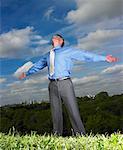 Businessman Standing in Field With Arms Open Wide