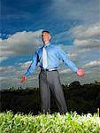 Businessman Standing in Field With Open Arms