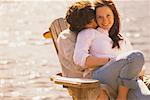 Jeune Couple câliner dans une chaise d'Adirondack sur la plage