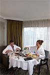 Couple de manger le petit déjeuner dans la chambre d'hôtel