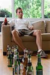 Man on Sofa with Many Empty Beer Bottles
