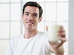 Man Holding Out a Glass of Milk