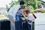 Couple Loading Luggage in Car Trunk