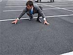 Businessman Crouching in Parking Lot