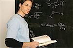 Young man standing in front of a blackboard